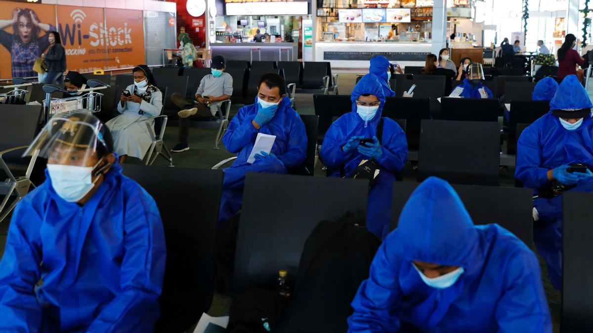 En el aeropuerto internacional de Soekarno Hatta se ven viajeros con trajes protectores contra el covid-19. 