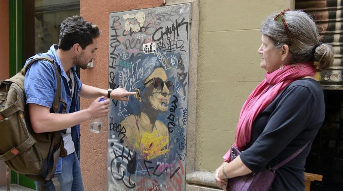 Dominic explica a Jane los detalles de un retrato grafiteado en la calle del Tiradors. Lo firma Rice.   