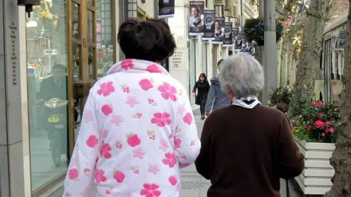 Dos personas caminan por la calle, una de ellas con un pijama