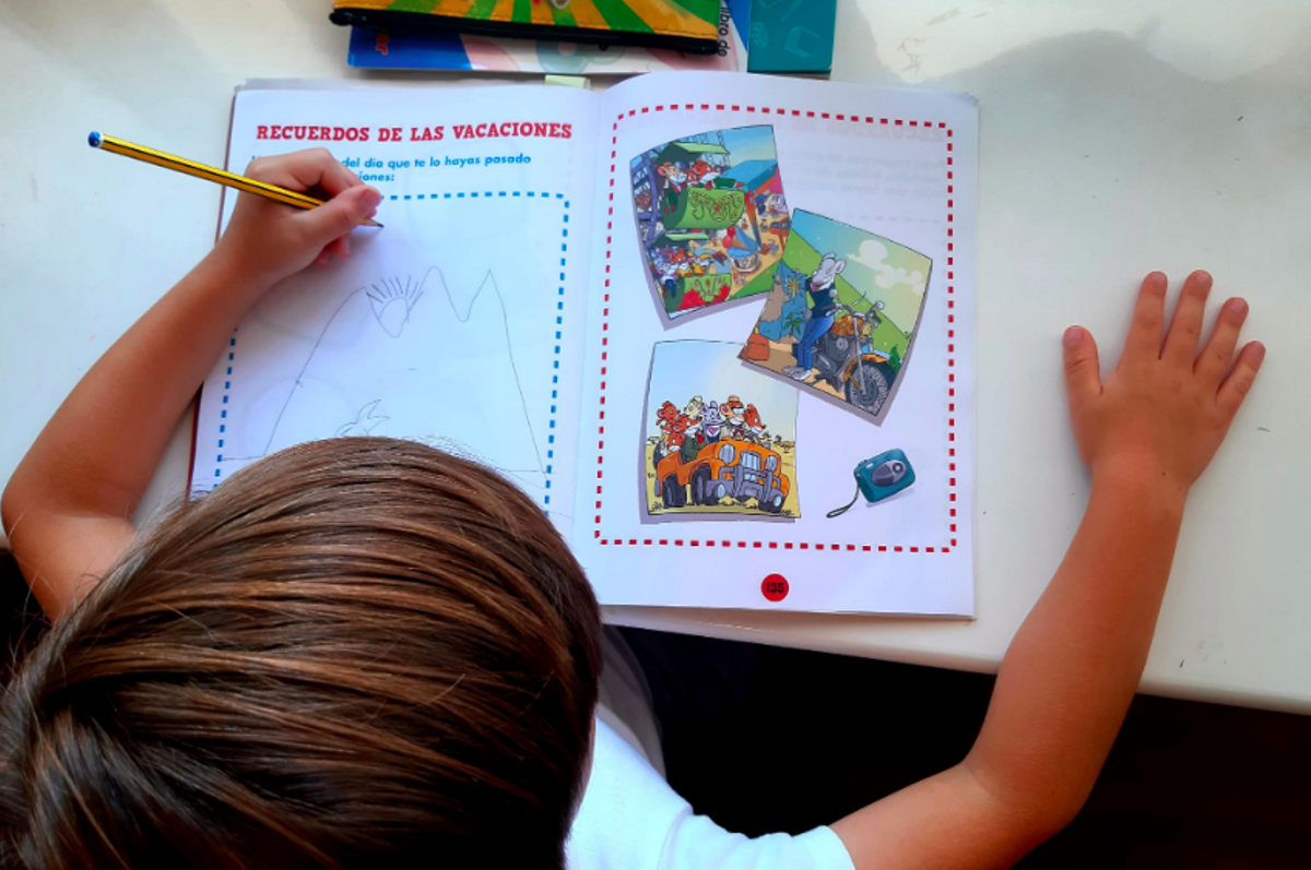 Un niño comenta los recuerdos de sus vacaciones en un cuaderno de verano Un niño comenta los recuerdos de sus vacaciones en un cuaderno de verano