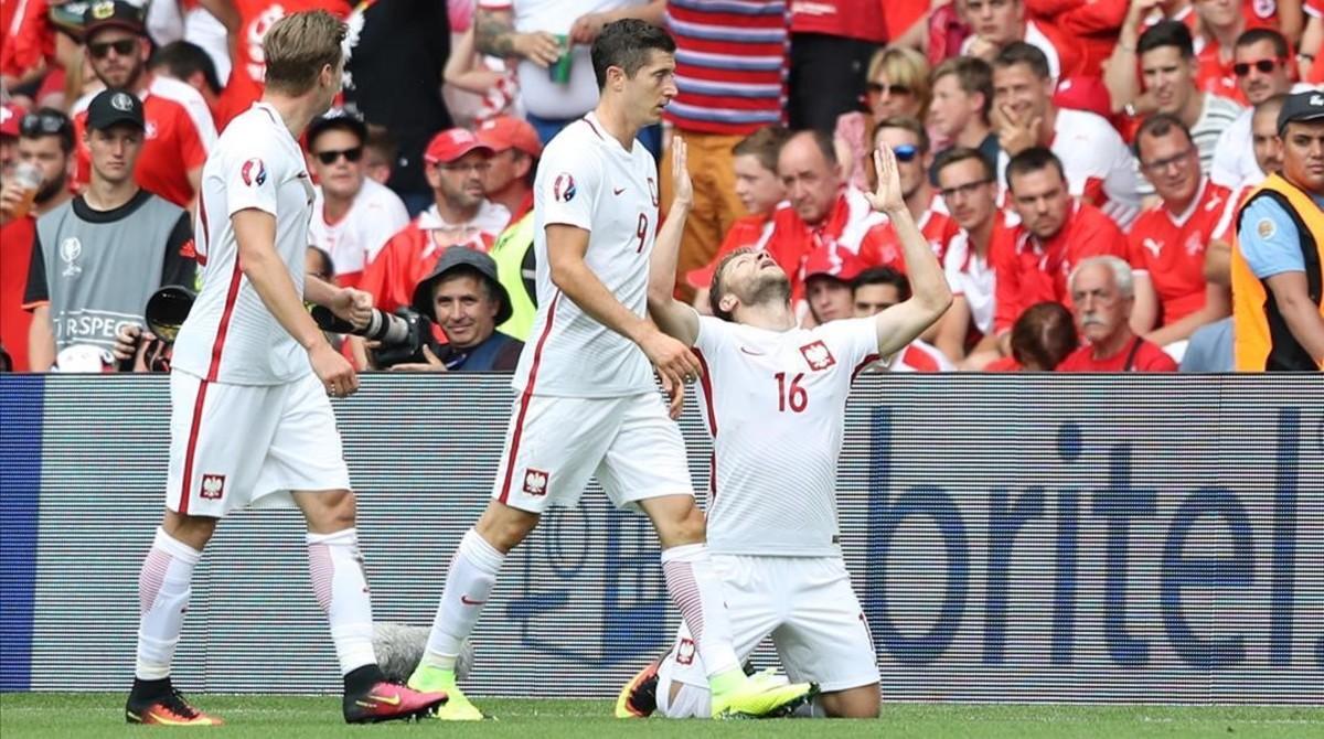 Blaszczykowski, arrodillado en el césped, celebra su gol a Suiza junto a Lewandowski.