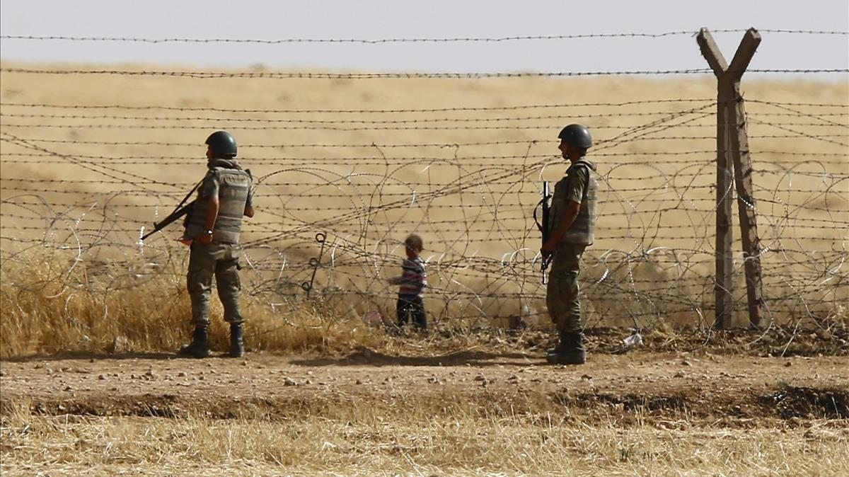 Un niño sirio espera tras las vallas de la frontera para cruzar hacia Turquía cerca de Akcacale (sureste), en el 2015.