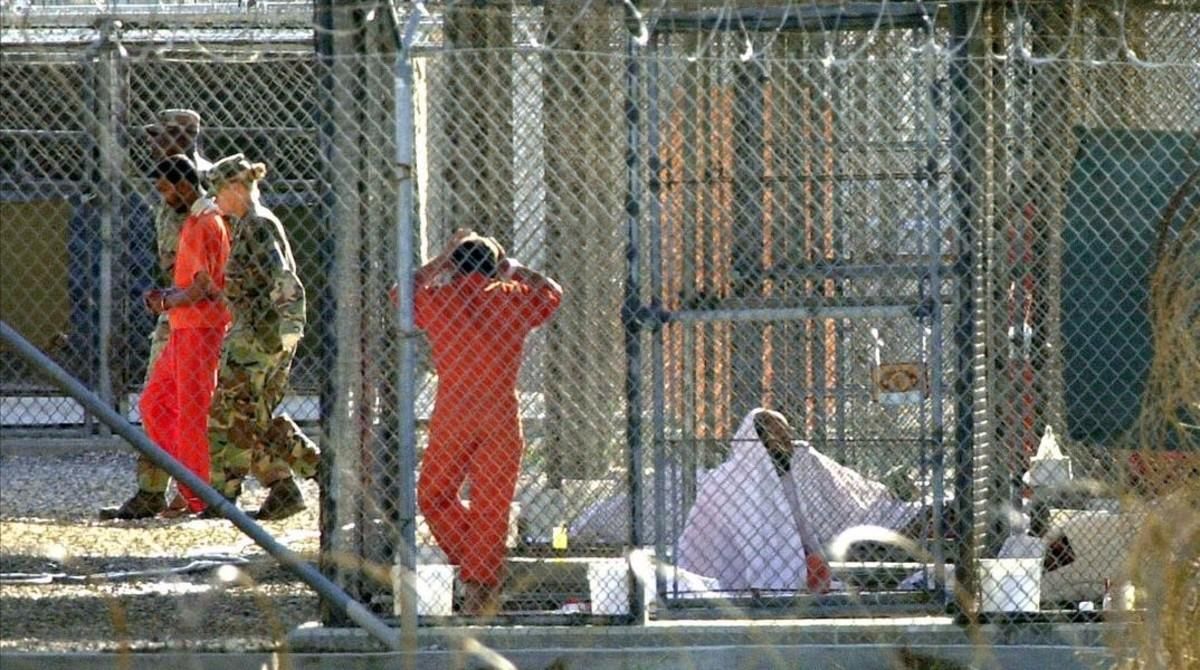 Un recluso de Guantánamo, escoltado por dos guardias en el penal, junto a otros dos presos en sus celdas. Un recluso de Guantánamo, escoltado por dos guardias en el penal, junto a otros dos presos en sus celdas.