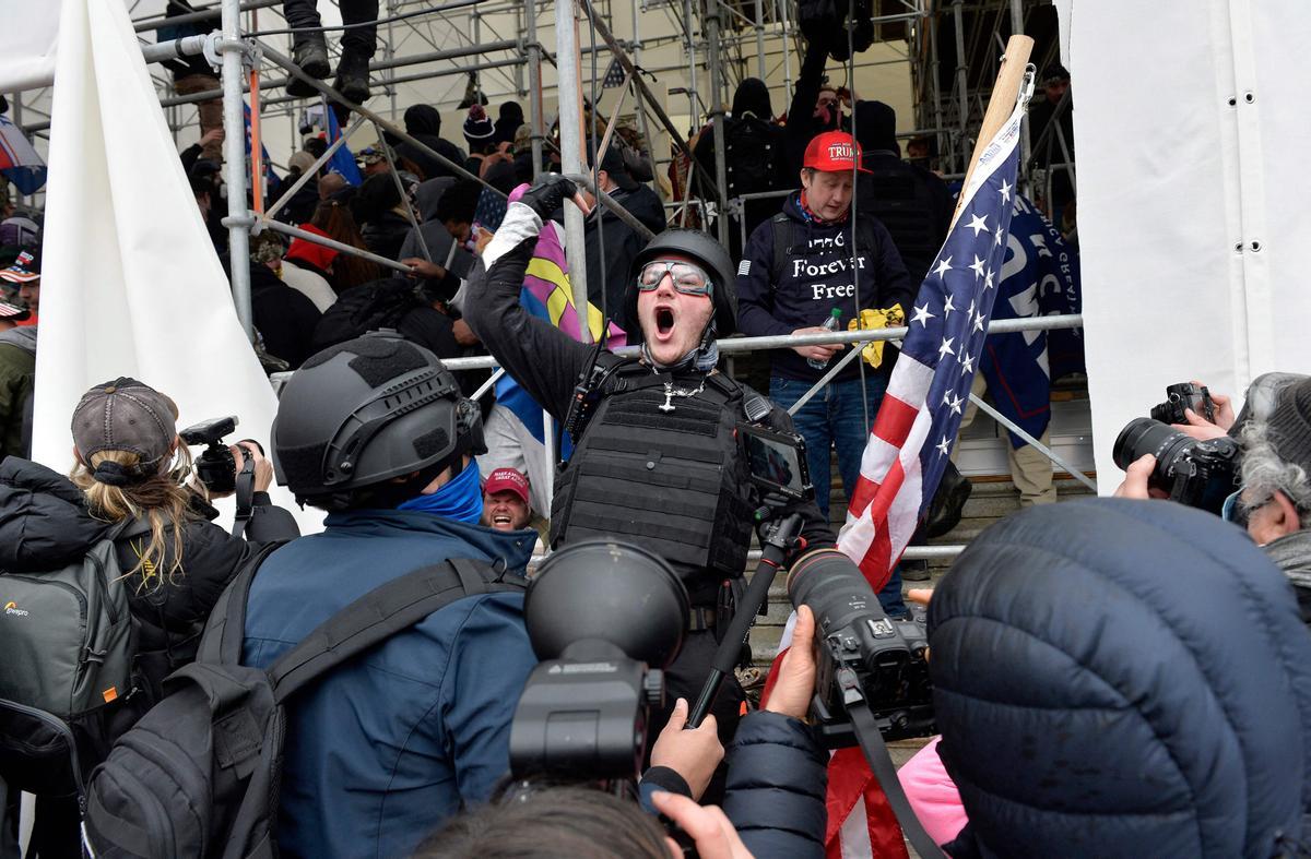 Un hombre pide a la gente que asalte el edificio mientras los partidarios de Trump chocan con la policía y las fuerzas de seguridad mientras intentan asaltar el Capitolio de EEUU.