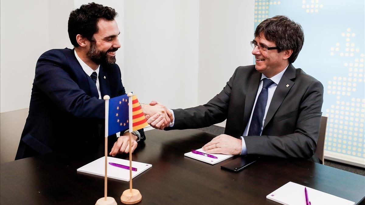 El expresidente de la Generalitat Carles Puigdemont estrecha la mano del presidente del Parlament, Roger Torrent, durante la reunión que ambos han mantenido este miércoles en Bruselas. El expresidente de la Generalitat Carles Puigdemont estrecha la mano del presidente del Parlament, Roger Torrent, durante la reunión que ambos han mantenido este miércoles en Bruselas.