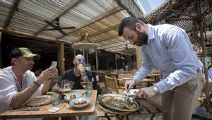 Un camarero sirve una mesa de dos turistas en un restaurante de la Barceloneta.