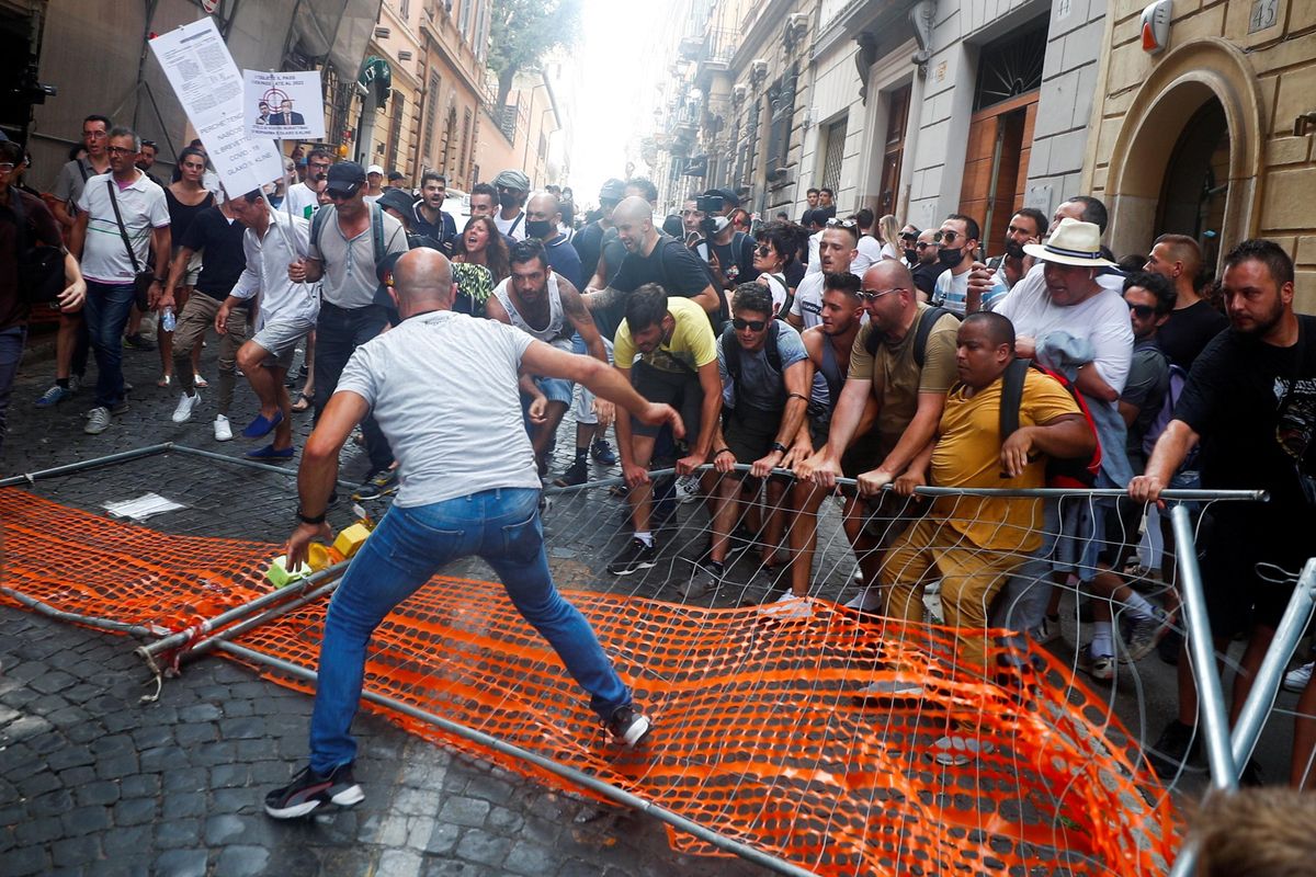 Un grupo de manifestantes contra el pasaporte covid aparta las vallas colocadas por la policía para prevenir su paso en Roma. Un grupo de manifestantes contra el pasaporte covid aparta las vallas colocadas por la policía para prevenir su paso en Roma.