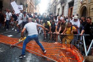 Un grupo de manifestantes contra el pasaporte covid aparta las vallas colocadas por la policía para prevenir su paso en Roma. 