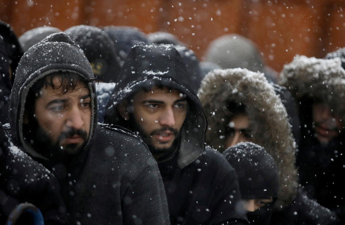 Un grupo de migrantes esperan bajo la nieve en un centro de transporte y logística en la región bielorrusa de Grodno, junto a la frontera con Polonia, este martes.