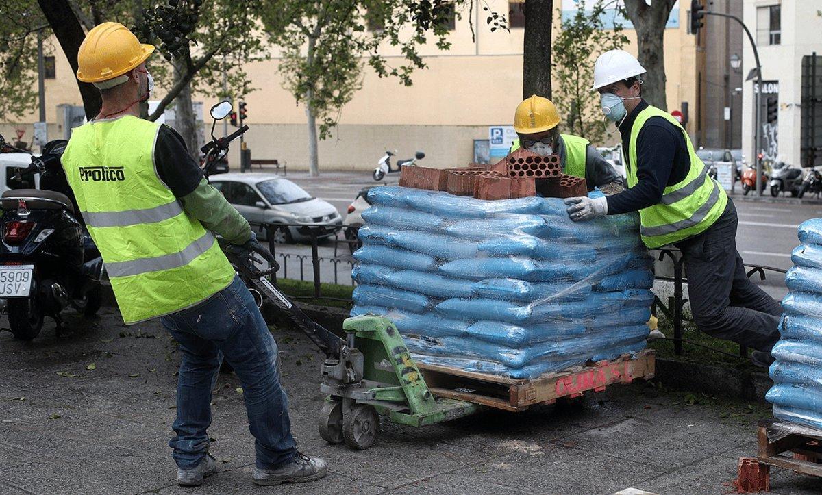 Varios obreros empujan material de construcción necesario para rehabilitar un edificio, en Madrid, el lunes pasado.