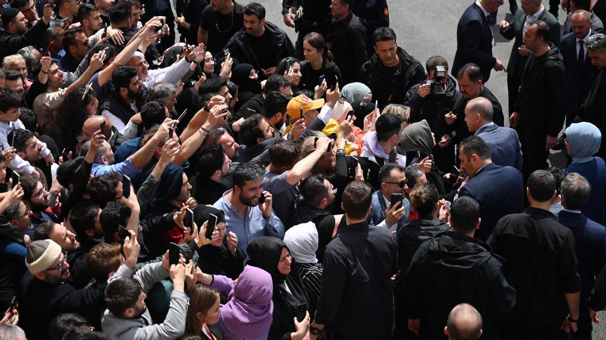 El presidente turco, Recep Tayyip Erdogan, y su esposa, Emine Erdogan, rodeados por la multitud cuando salen del colegio electoral después de votar en las elecciones presidenciales y parlamentarias, en Estambul, Turquía.