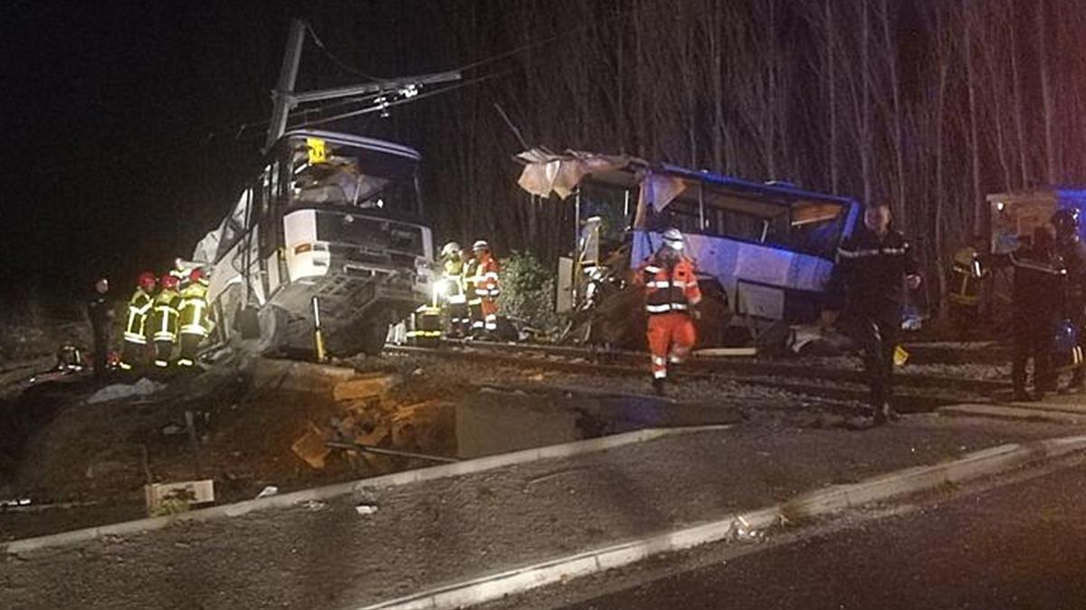 Varios trabajadores retiran los restos del autobús que se ha partido en dos tras el choque con el tren. 