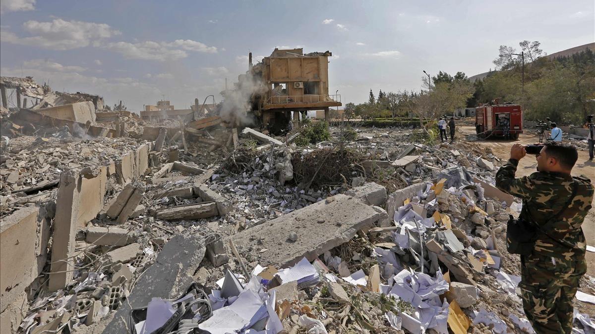 Un soldado sirio toma fotos de los escombros de un edificio bombardeado en la operación liderada por EEUU, que formaba parte del Centro de Estudios e Investigaciones Científicas, en Damasco, este sábado.