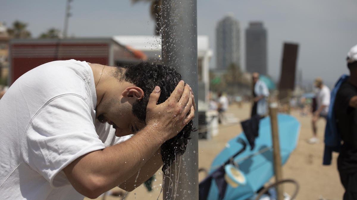 Día de calor extremo en Barcelona. En la imagen, un hombre se refresca en la playa de la Barceloneta.
