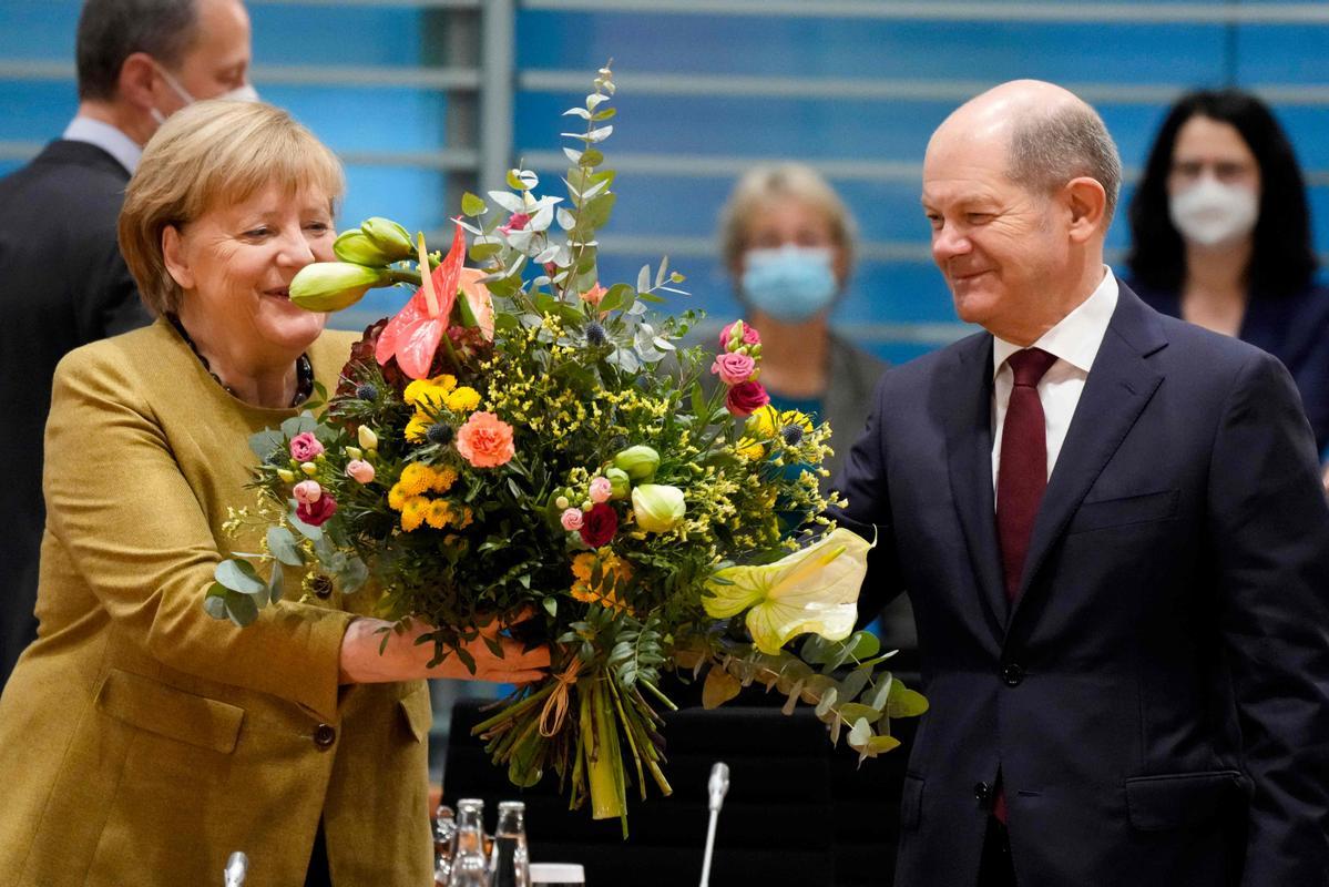 Angela Merkel recibe un ramo de flores. 