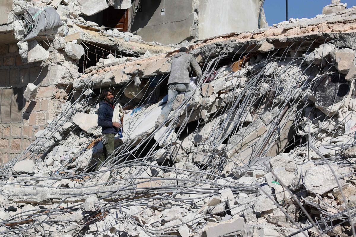 Dos hombres trabajan entre los escombros de un edificio derrumbado por el terremoto en la población siria de Atarib, en Alepo, en territorio bajo control opositor.