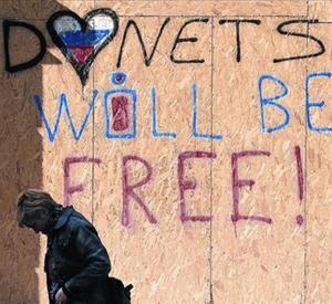 Una mujer pasa frente a un muro con la frase «Donetsk será libre».