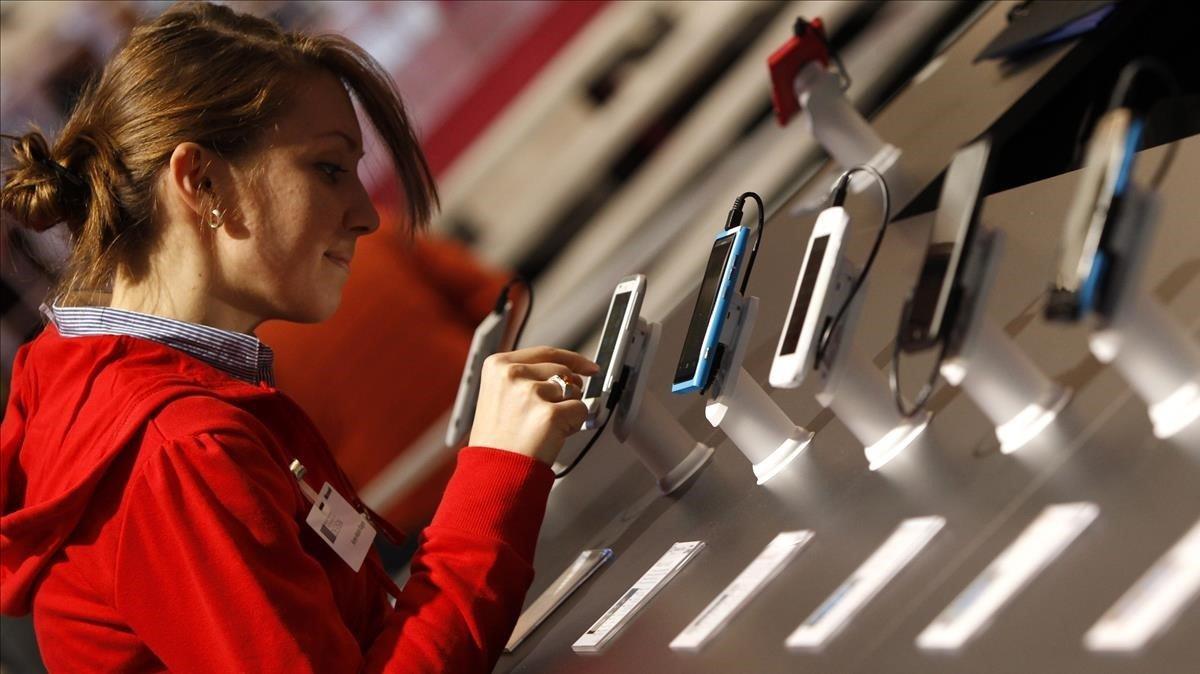 Una trabajadora de Deutsche Telekom comprueba el funcionamiento de un móvil en una feria informártica en Hanover.