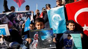 Ethnic Uighur boys hold placards with the images of English soccer club Arsenal’s midfielder Mesut Ozil during a protest against China in Istanbul, Turkey December 14, 2019. The placard reads: Thank you, Mesut Ozil, on behalf of 35 million oppressed.  REUTERS/Kemal Aslan NO RESALES. NO ARCHIVES