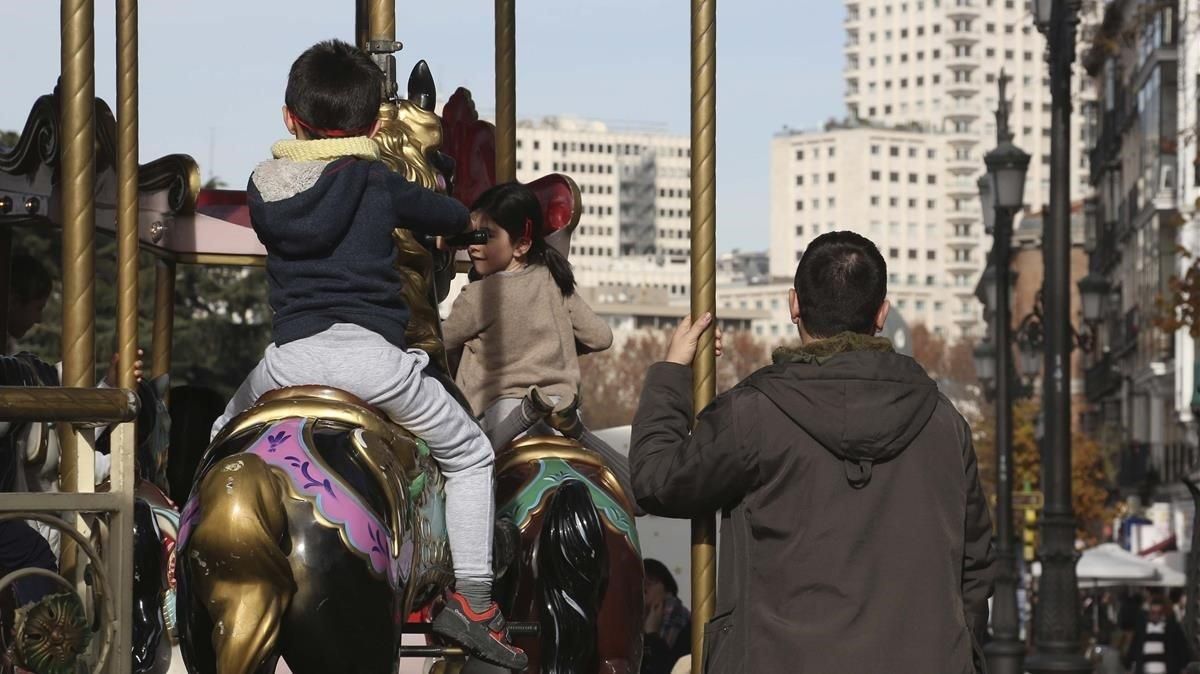 Unos niños montan en un tiovivo en presencia de adultos, en Madrid. Unos niños montan en un tiovivo en presencia de adultos, en Madrid.