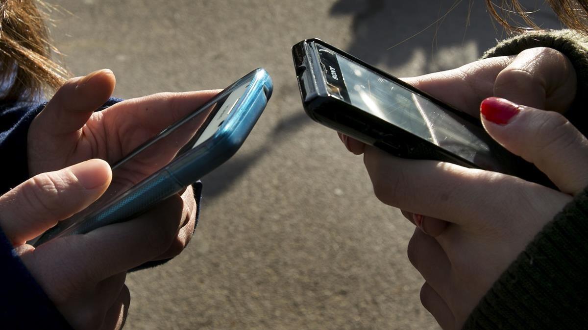 Una foto de archivo con dos personas escribiendo en sus teléfonos móviles
