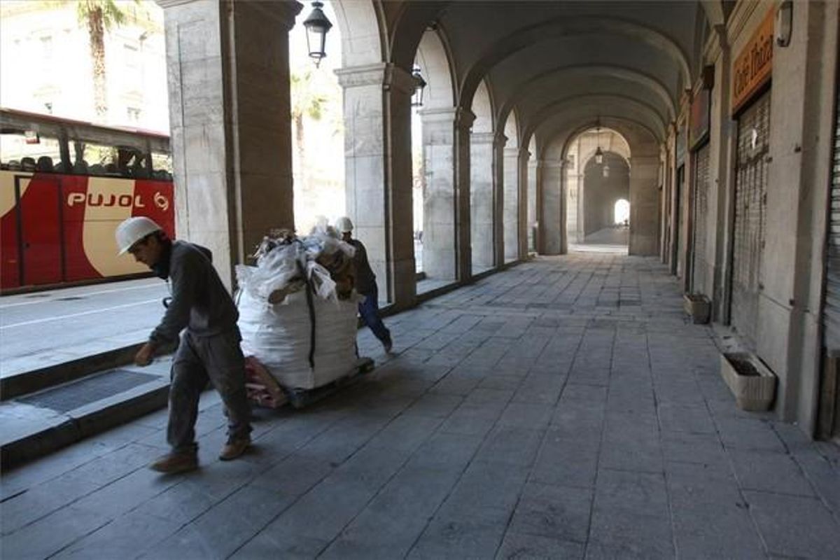Dos obreros retiran una bolsa llena de escombros de una de las fincas en rehabilitación del entorno de los porches de Xifré. Dos obreros retiran una bolsa llena de escombros de una de las fincas en rehabilitación del entorno de los porches de Xifré.