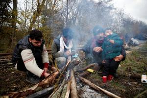 Un grupo de migrantes trata de calentarse frente a una hoguera en un campamento improvisado en las inmediaciones de Calais. 