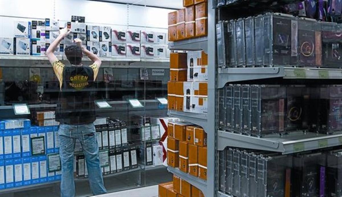 Un trabajador de una tienda de informática de Barcelona coloca nuevos productos en uno de los estantes, ayer.
