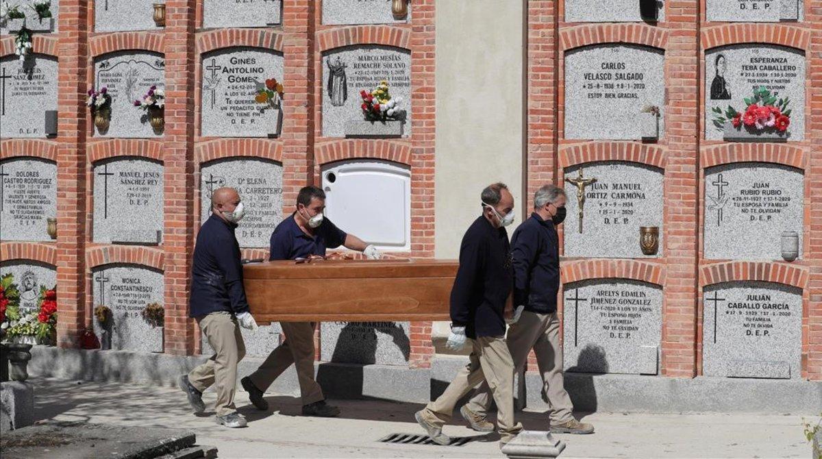 Operarios trasladan un féretro en el cementerio de la Almudena, en Madrid.