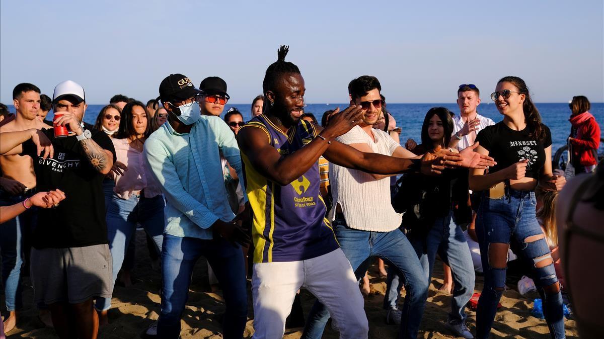 Gente bailando en la playa de la Barceloneta sin respetar las medidas de seguridad del covid. 