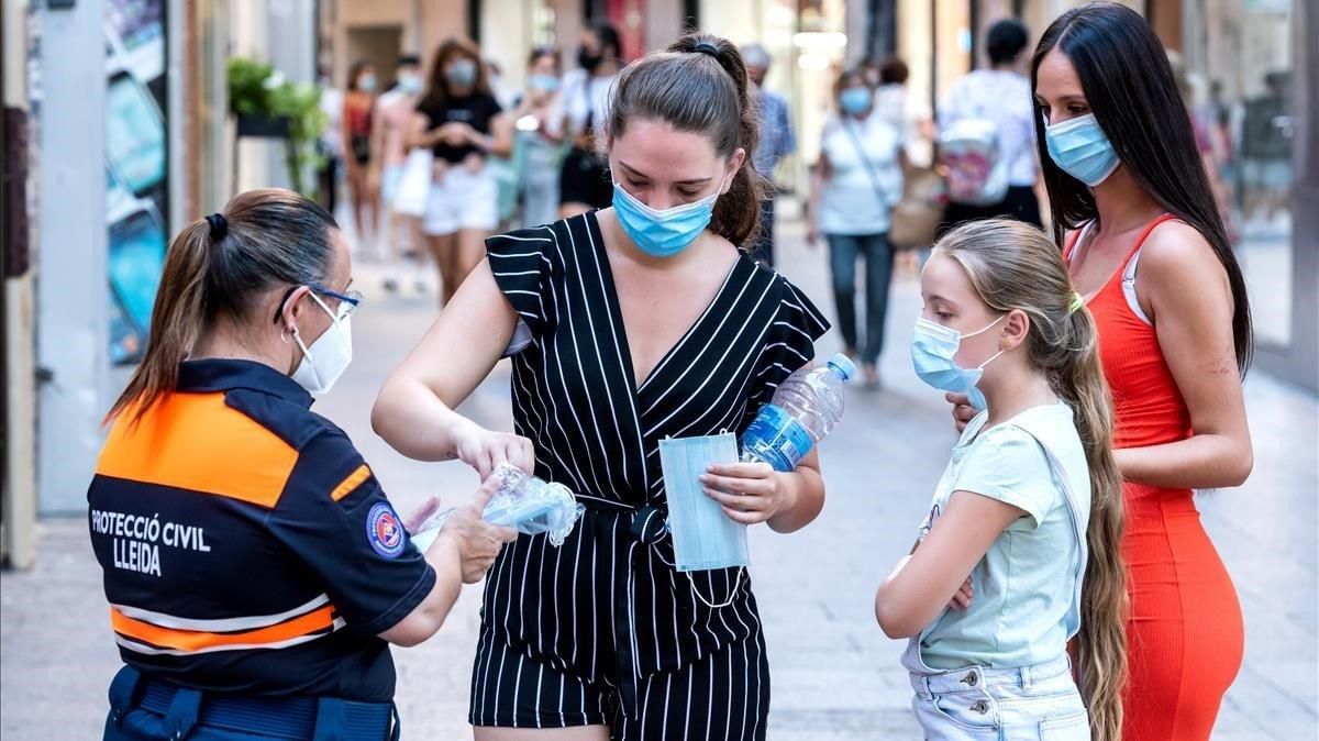 Una agente de Protección Civil distribuye mascarilas en el Eix Comercial de Lleida, este lunes. Una agente de Protección Civil distribuye mascarilas en el Eix Comercial de Lleida, este lunes.