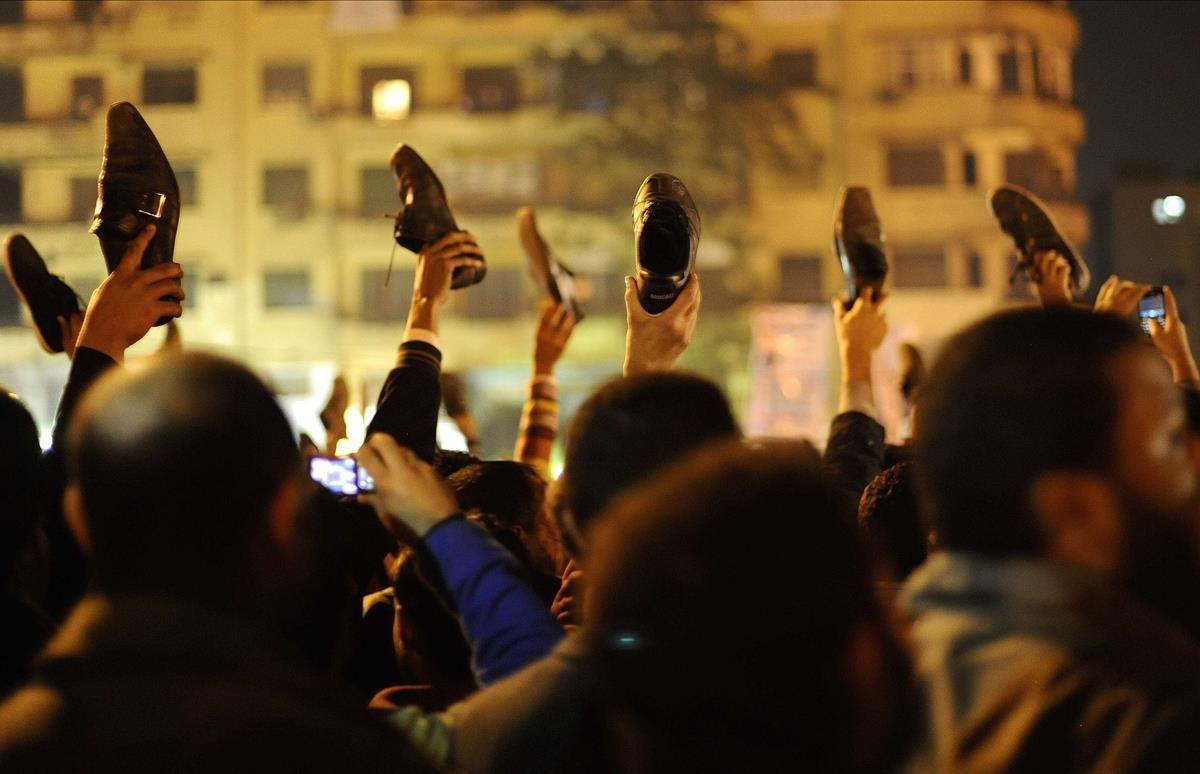 Manifestantes en contra del gobierno se manifiestan en la plaza Tahrir de El Cairo mostrando zapatos en alto en señal de consternación, mientras Hosni Mubarak se dirige a la nación, el 10 de febrero del 2011.