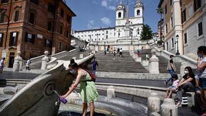 Turistas cogen agua en la fuente de la plaza de España en Roma.