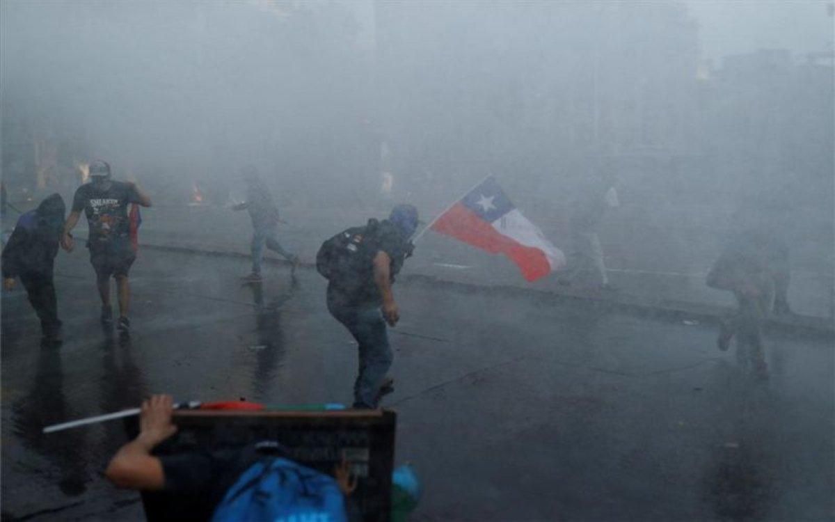 Los manifestantes en Chile se resguardan del ataque de la Polícia. Los manifestantes en Chile se resguardan del ataque de la Polícia.