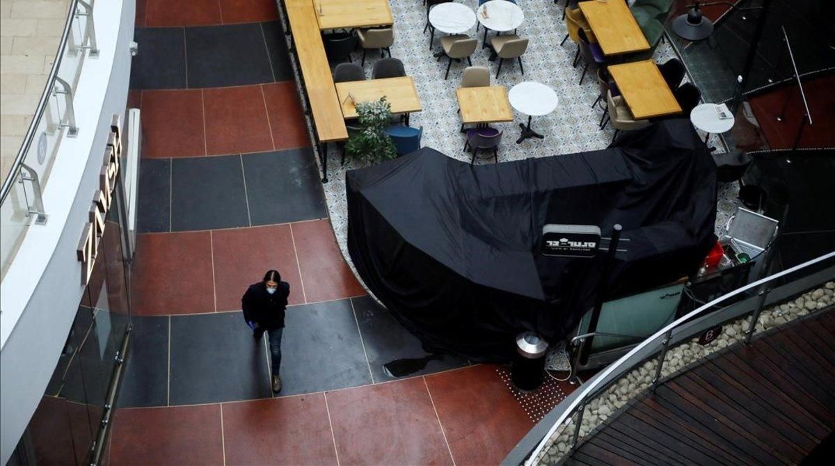 Un israelí con máscara en un centro comercial vacío. Un israelí con máscara en un centro comercial vacío.