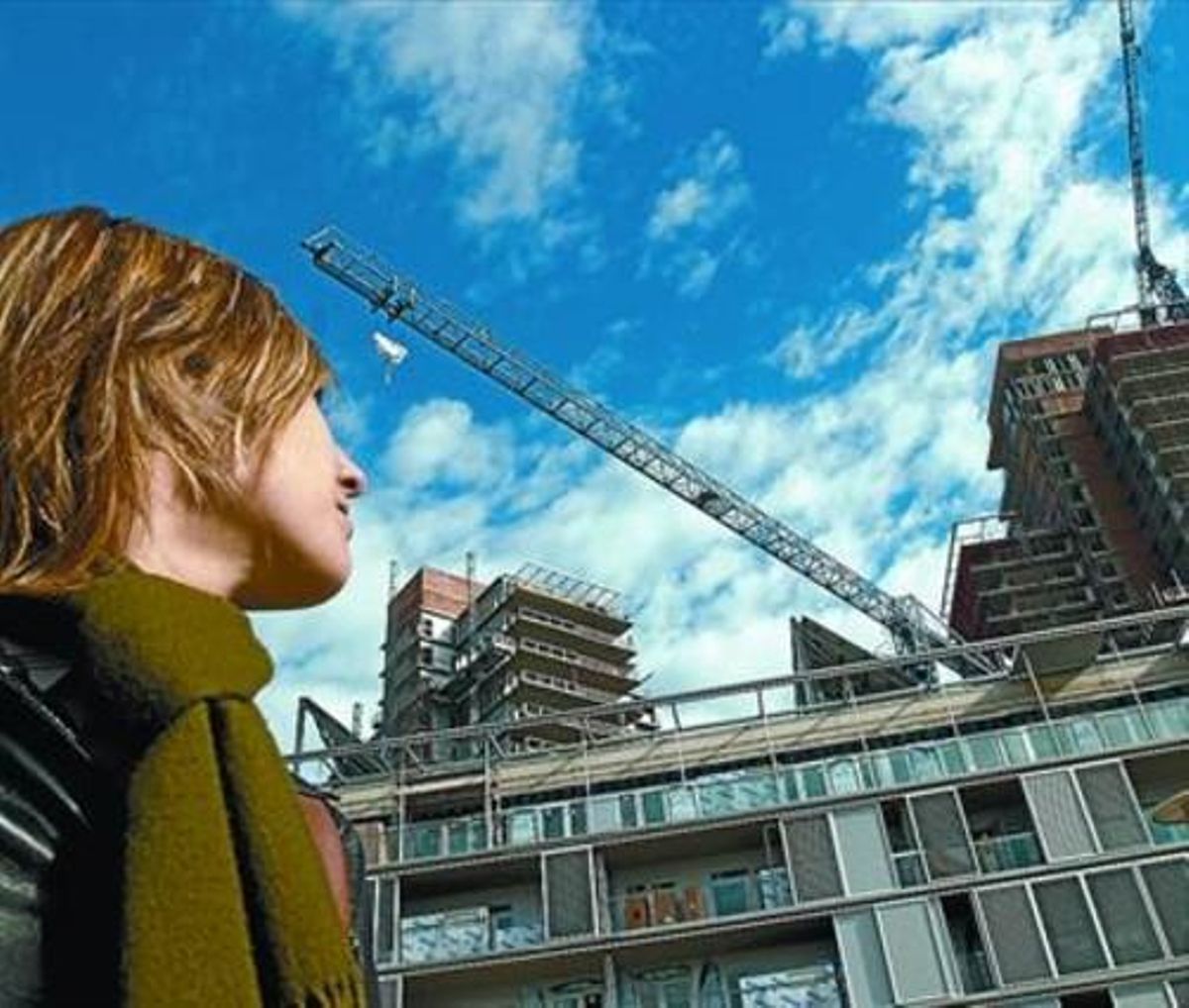Una joven observa unas obras de construcción de pisos en Barcelona. Una joven observa unas obras de construcción de pisos en Barcelona.