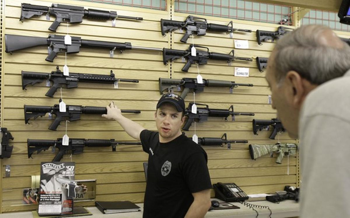 El dependiente de una tienda de armas de Fort Worth (Tejas) explica las características de un rifle a un cliente. El dependiente de una tienda de armas de Fort Worth (Tejas) explica las características de un rifle a un cliente.