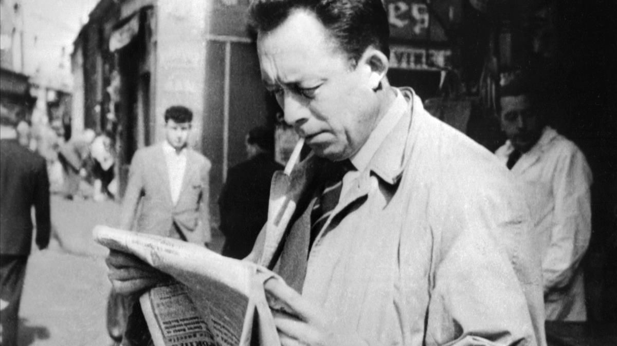 Albert Camus en 1959, leyendo el diario en las calles de París. Albert Camus en 1959, leyendo el diario en las calles de París.