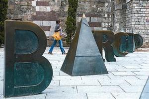 LlegatLes lletres de Bàrcino, a la plaça Nova, i l’antifaç daurat que Brossa va dissenyar per als premis FAD Sebastià Gasch al terra de la Rambla, a l’altura del Carme.