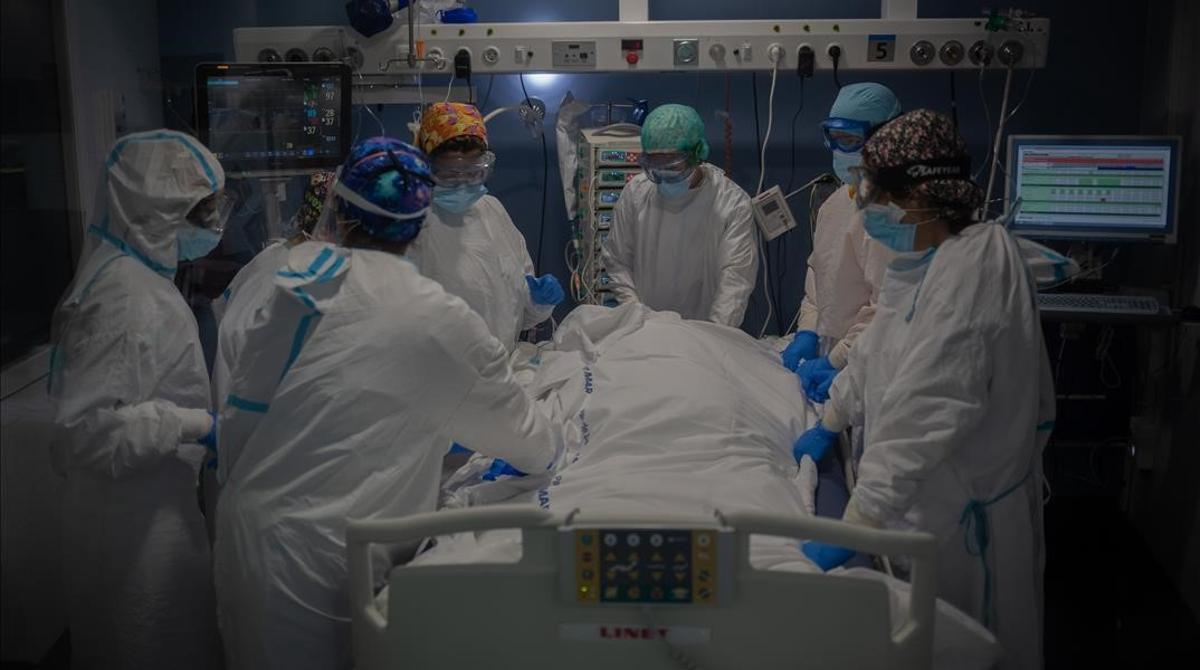 Trabajadores sanitarios protegidos atienden a un paciente en la uci del Hospital del Mar, en Barcelona.