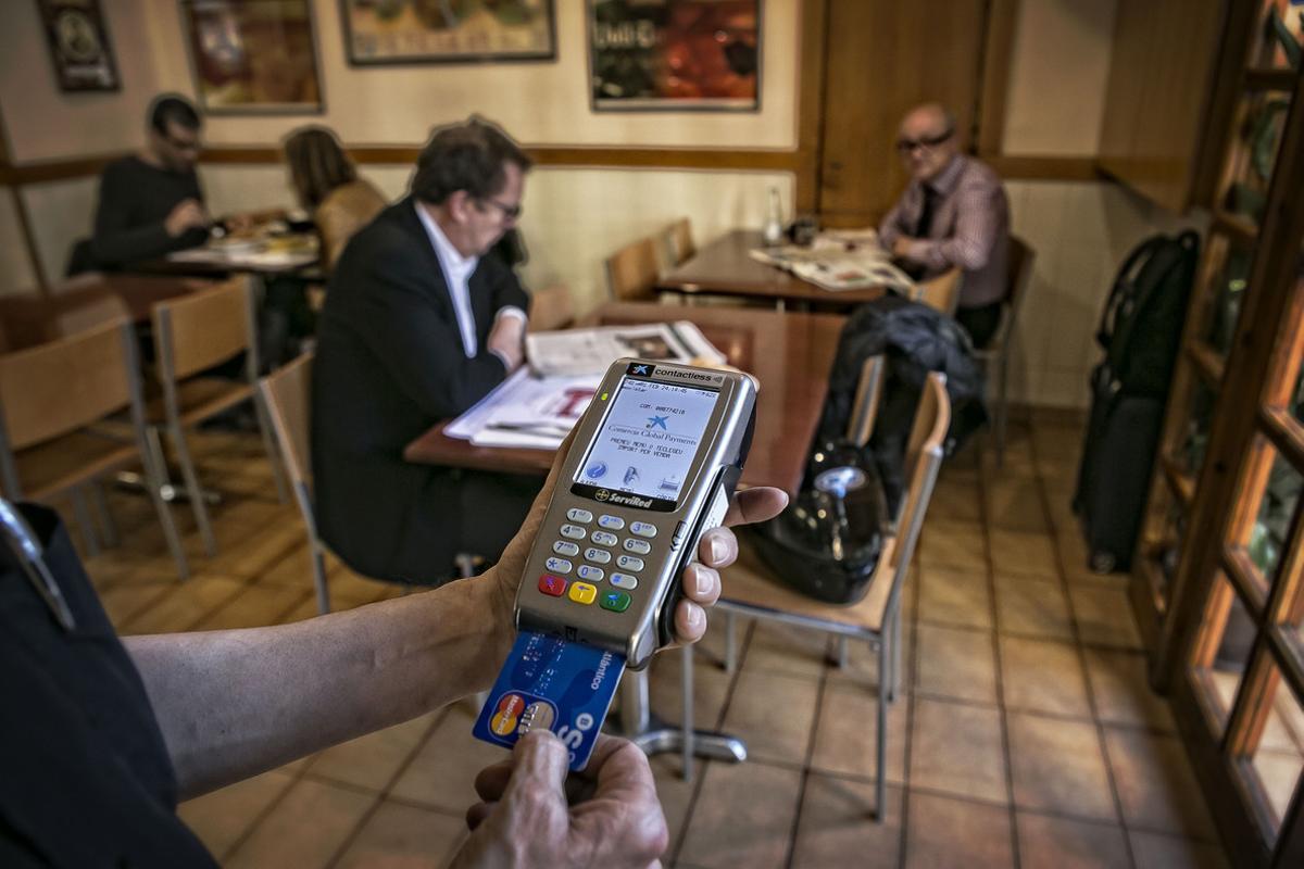 Un camarero cobra con un datáfono a un cliente de un bar de Barcelona. Un camarero cobra con un datáfono a un cliente de un bar de Barcelona.