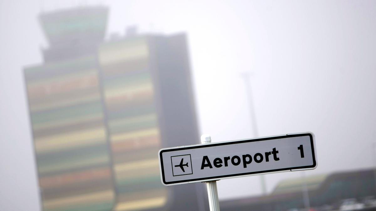 Señal que dirige al aeropuerto de Lleida-Alguaire, con la torre de control visible entre la niebla.