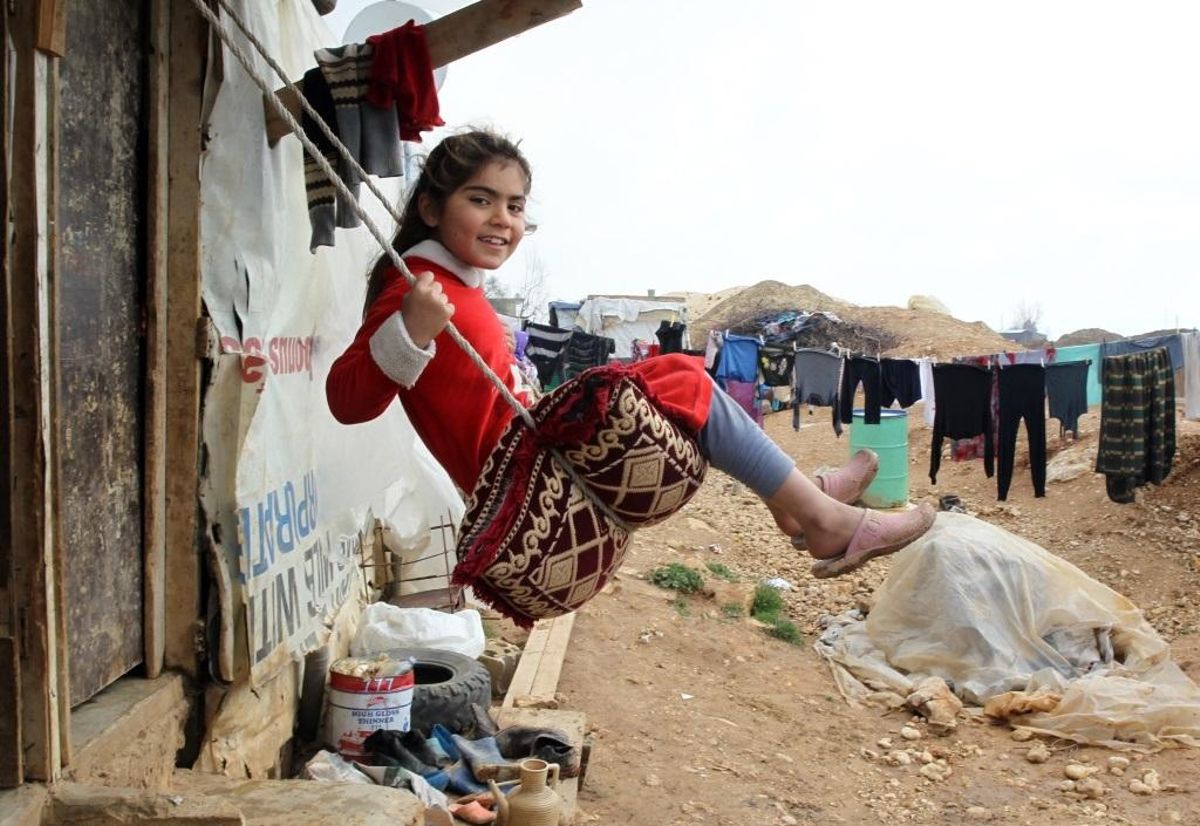 Una niña siria se columpia en un campamento de refugiados. Una niña siria se columpia en un campamento de refugiados.